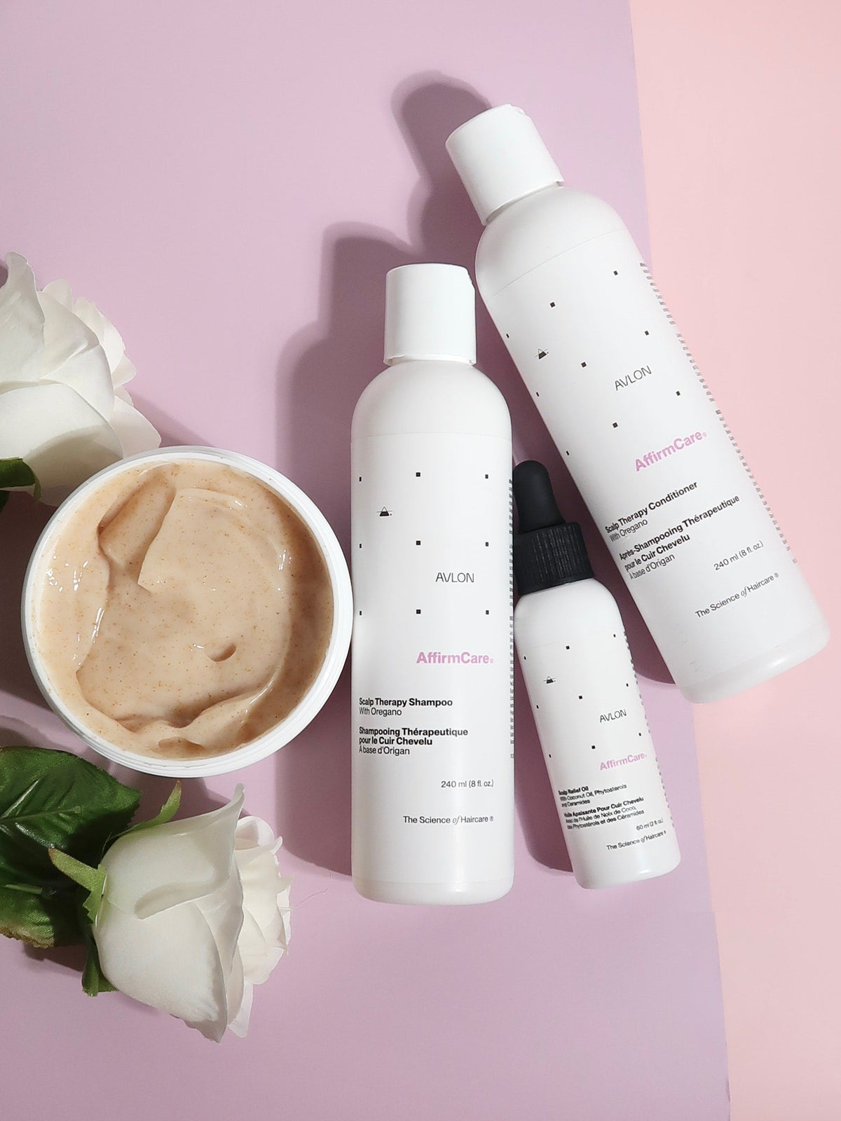 AffirmCare Scalp Therapy products arranged with an open jar of exfoliating masque on a pink background.
